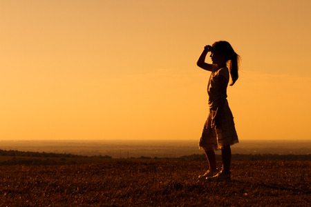Cute little girl enjoys watching sunset.の写真素材