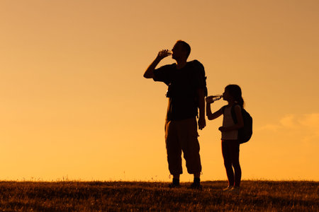 Silhouette of father and daughter resting of hiking and drinking water.の写真素材