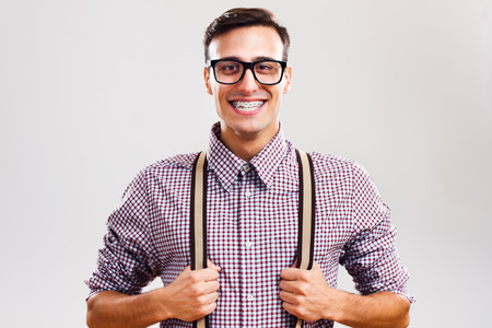 Portrait of funny handsome nerd guy pulling his suspenders.の写真素材
