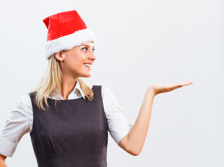 Portrait of beautiful happy business woman with Santa Hat holding your product.の写真素材