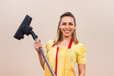 Portrait of beautiful housewife holding vacuum cleaner.の写真素材