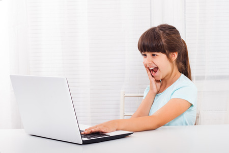 Little girl is using laptop and she is surprised because of something she saw on it.の写真素材