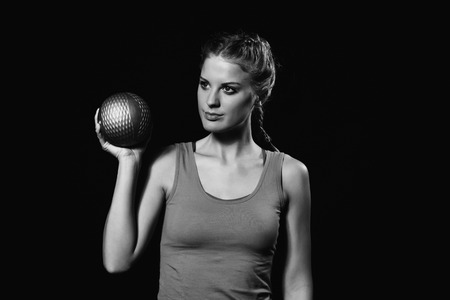 Beautiful young woman is exercising with medicine ball.Image is intentionally black and white.の写真素材