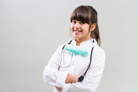 Portrait of beautiful little doctor on gray background.の写真素材