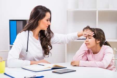 Female doctor checking temperature of sick child at medical office.の写真素材