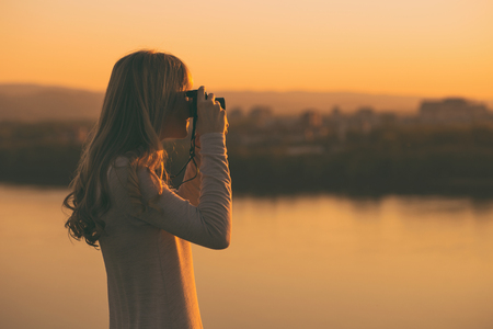 Silhouette of a woman photographing at the sunset.Image is intentionally toned.の写真素材