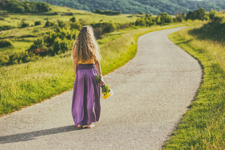 Woman with beautiful blonde hair holding bouquet of flowers and enjoys in the nature.Image is intentionally toned.の写真素材