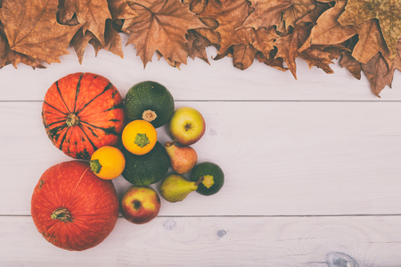 Image of pumpkins,apples and pears on wooden table with autumn leaves. Image is intentionally toned.の写真素材