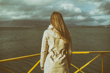 Woman standing at the harbor in Reykjavik and looking at the sea.Image contains little noise because of high ISO set on camera and it is intentionally toned.の写真素材