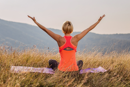 Happy fitness woman enjoys relaxing in the nature after exercise with her arms outstretched.Image is intentionally toned.の写真素材