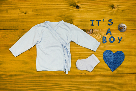 Text it's a boy with baby supplies and heart shape on wooden table.Toned photo.の写真素材