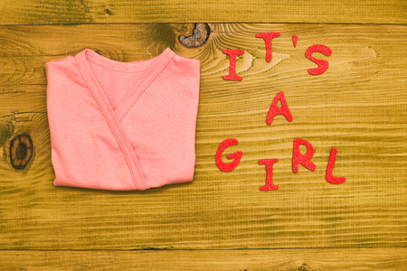 Text it's a girl with little baby t-shirt  on wooden table.Toned photo.の写真素材
