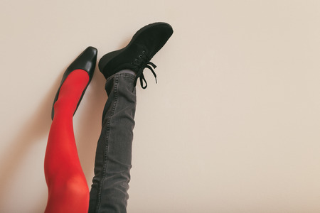 Legs of a woman in red tights and high heels and sport shoe and jeans.Toned photo.の写真素材