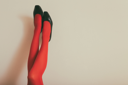 Beautiful legs  of a woman in red tights and high heels up in front of wall.Toned photoの写真素材