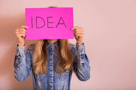 Woman holding paper with word idea while standing in front of the wall.の写真素材