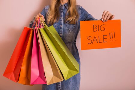 Woman holding shopping bags with paper with text big sale while standing in front of the wall.の写真素材