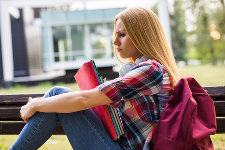 Tired and angry female student  studying while sitting outdoor.の写真素材