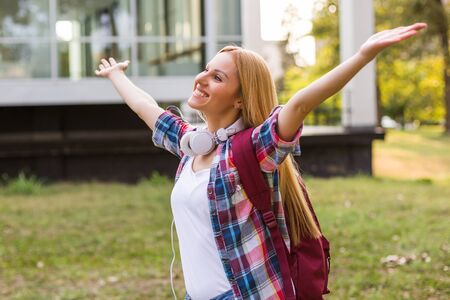 Female student with arms outstretched enjoys spending time outdoor.の写真素材