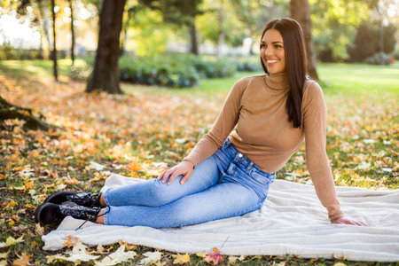 Beautiful woman enjoys in autumn while resting in the park.