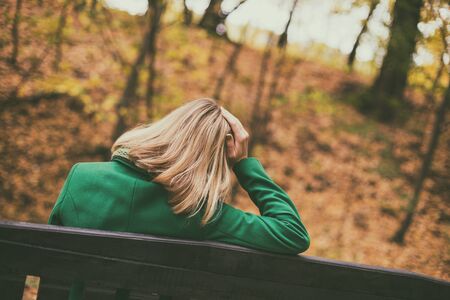 Sad woman sitting on a bench in the park.の写真素材