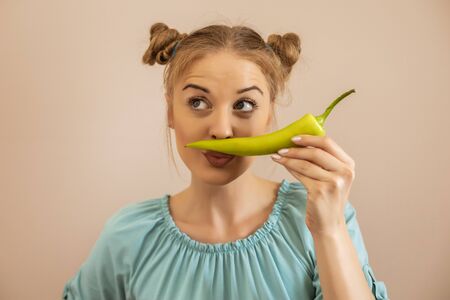 Cute playful woman holding green pepper.Toned image.の写真素材