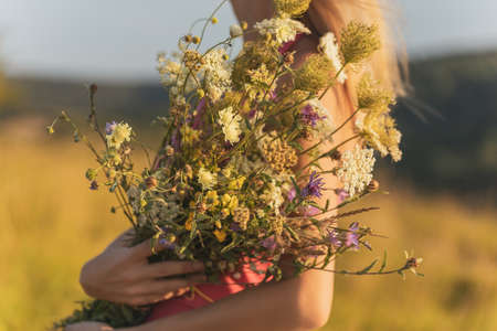 Woman holding bouquet of flowers and enjoys in the nature.Focus on flowers.の写真素材