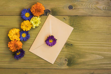 Beautiful flower petals and closed  envelope on wooden background.の写真素材