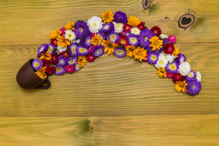 Image of beautiful flowers and coffee or tea cup on wooden background.