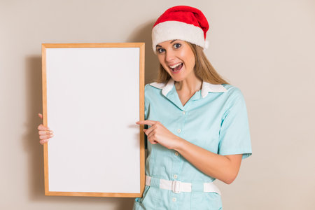 Portrait of nurse with Santa hat pointing at white board.の写真素材