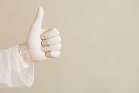 Image of close up hand in protective glove of doctor showing thumb up.の写真素材