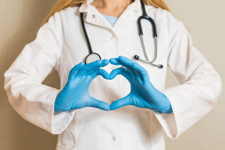 Image of female doctor showing heart shape with hands.の写真素材