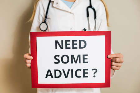 Image of female doctor holding a paper with a text need some advice.の写真素材