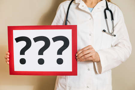 Image of female doctor holding a paper with a question marks.の写真素材