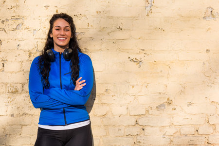 Portrait of beautiful sporty woman standing in front of wall.
