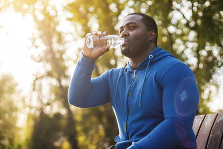 Man resting on bench after exercise and drinking water .