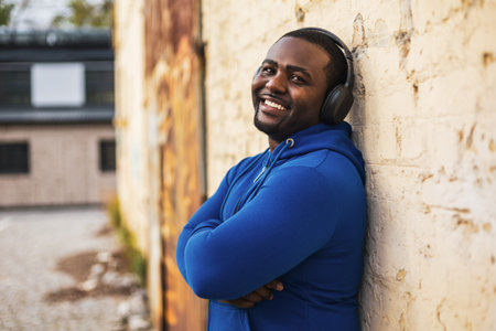 Sporty man with headphones enjoys listening music outdoor.