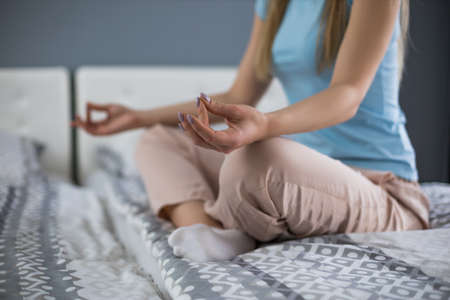 Close up hands of woman meditating on bed in her bedroom.Focus on hand.の写真素材