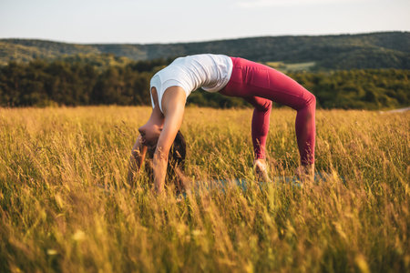 Beautiful woman doing yoga in the nature,Urdhva Dhanurasana/Upward bow pose.