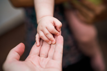 Close up image of  father's   and his baby boy son hands holding each other. Focus on fingers.の写真素材