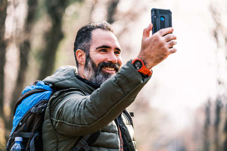 Image of man enjoys hiking and making selfie with his phone.の写真素材