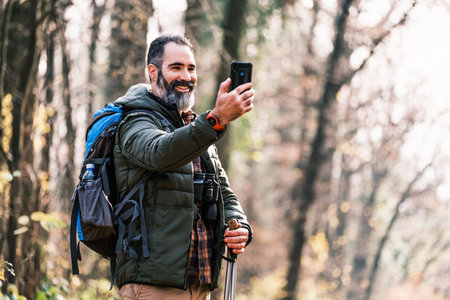 Image of man enjoys hiking and making selfie with his phone.の写真素材
