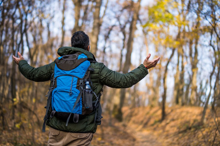 Man hiker with arms raised enjoys in beautiful view in the nature.