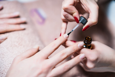Close up image of manicure process, manicurist applying  gel nail polish on female fingernails. Focus on fingernail.の写真素材