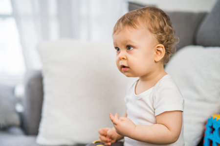 Portrait of cute little baby boy playing  while  sitting on sofa .
