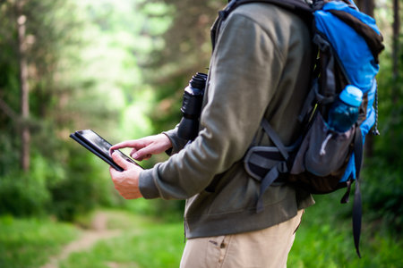 Image of hiker using digital tablet while spending time in nature.の写真素材