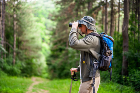 Image of man hiking and using binoculars.