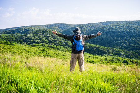 Man hiker with arms raised enjoys in beautiful view in the nature.の写真素材