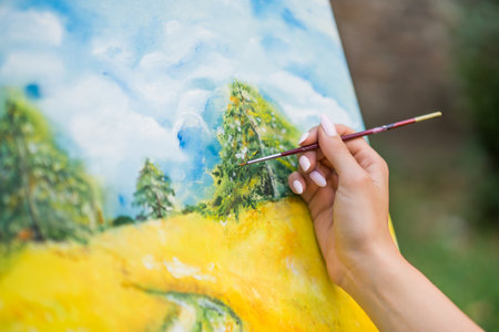 Woman enjoys woman painting on canvas outdoor.の写真素材