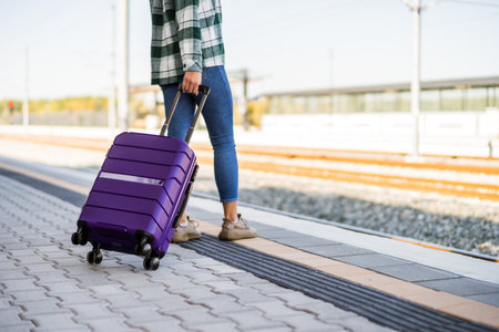 Woman with suitcase standing on train station.の写真素材