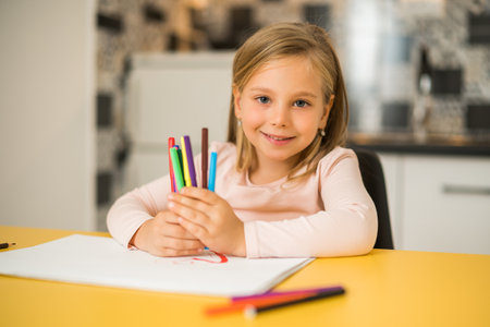 Beautiful little girl enjoys drawing at her home.の写真素材